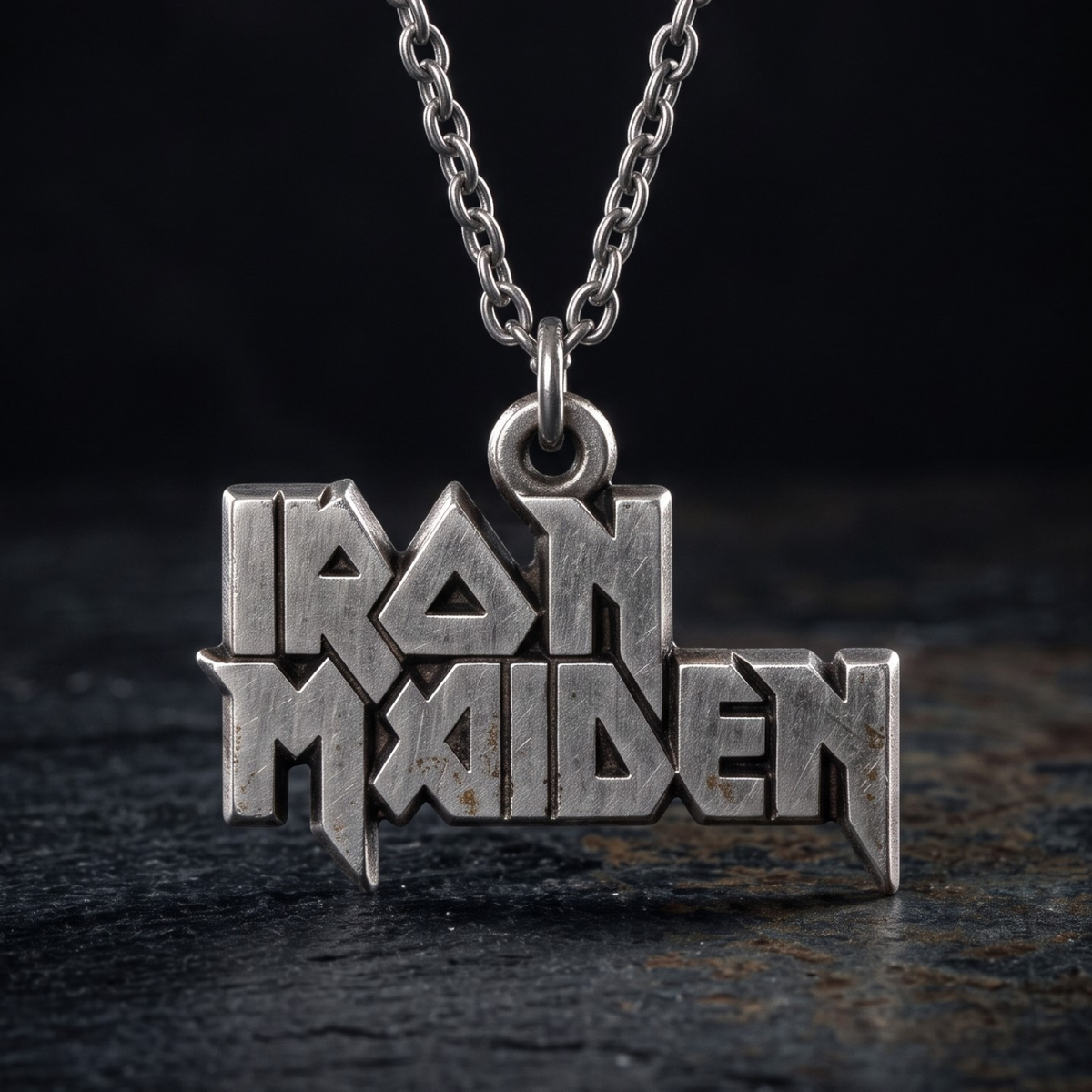 We Rock Iron Maiden logo pendant necklace in distressed silver metal on a dark textured background